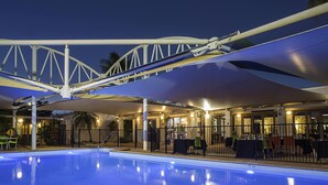 A swimming pool with a covered area, a bridge structure, and a restaurant with outdoor seating. - ibis Styles Karratha (Karratha)