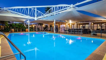 Una piscina con una estructura de toldo blanco, rodeada por una cerca y un área de estar al aire libre.