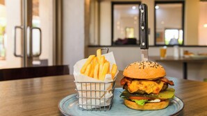 A plate with a burger and a basket of fries on a wooden table. - ibis Styles Karratha (Karratha)
