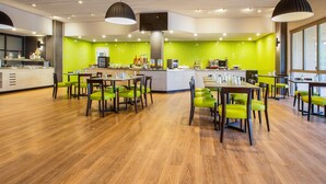A modern restaurant with a green herringbone wall, wooden flooring, and green chairs. - ibis Styles Karratha (Karratha)