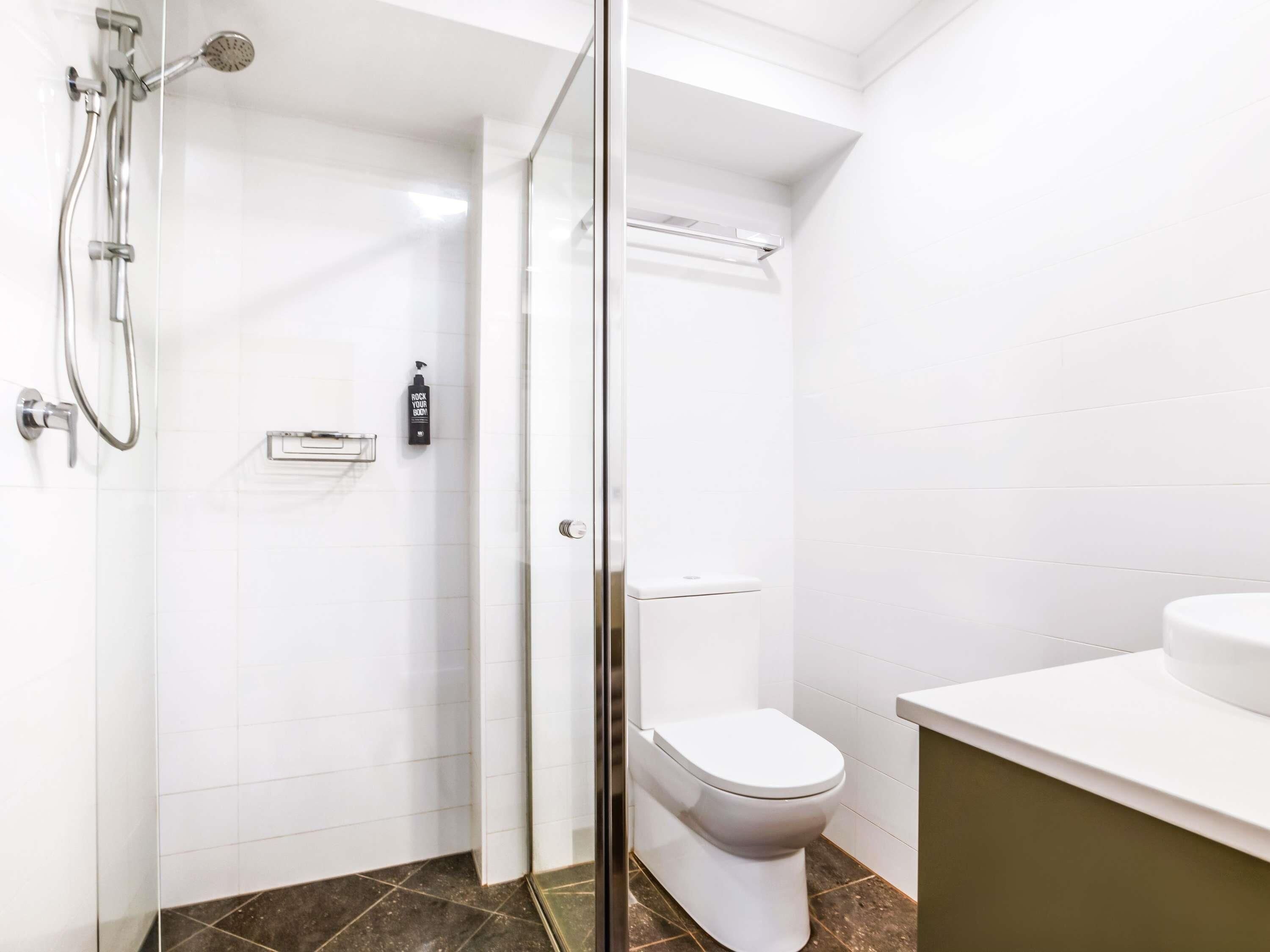 A modern bathroom with a glass shower enclosure, a toilet, and a sink.