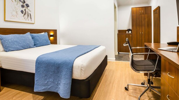 A hotel room with a bed, a desk with a chair, a wardrobe, and a painting on the wall. - ibis Styles Karratha (Karratha)