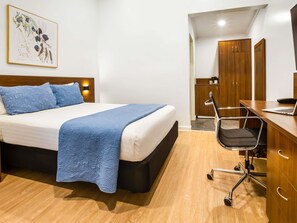 A hotel room with a bed, a desk with a chair, a wardrobe, and a painting on the wall. - ibis Styles Karratha (Karratha)
