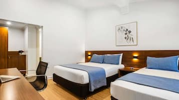 A hotel room with two beds, a desk, and a chair.