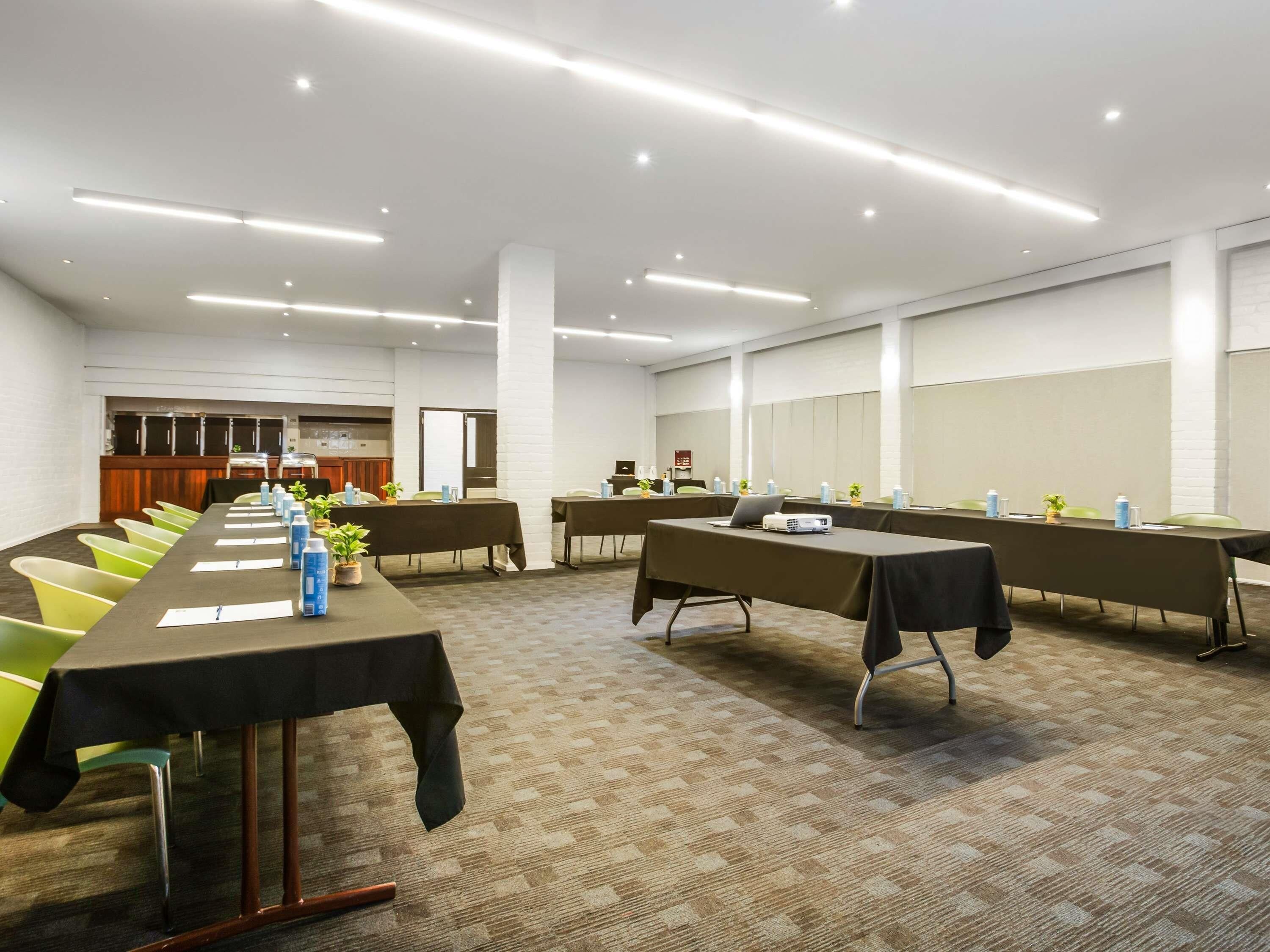 A conference room with long tables, chairs, and a projector.