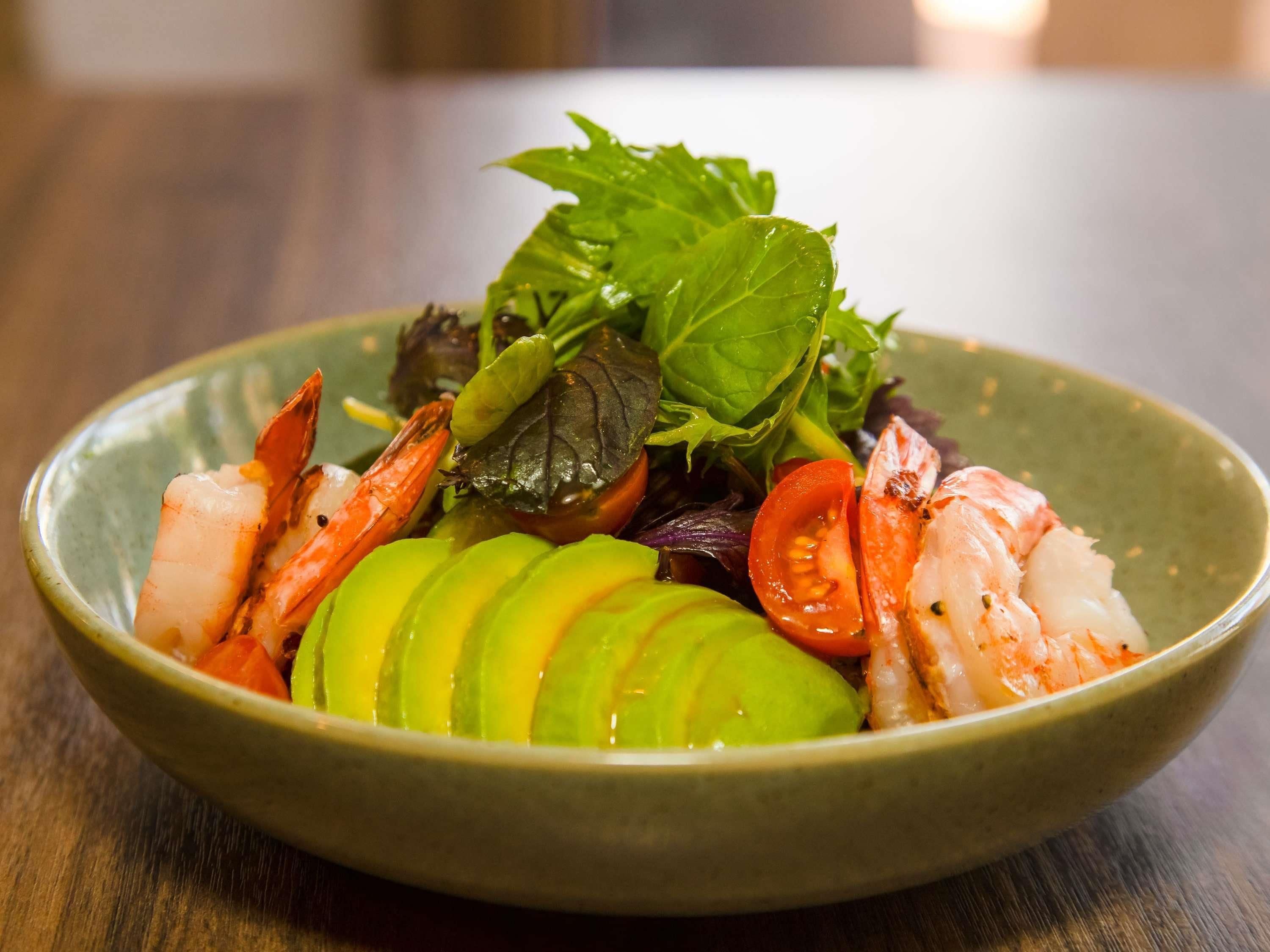 A bowl of seafood salad with avocado and greens.