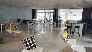 A spacious dining area with modern chairs and tables, large windows, and a view of the city.