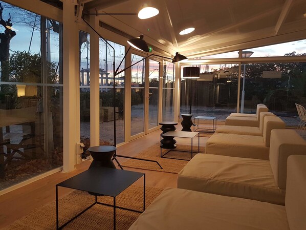 Relax in a stylish indoor space with a view of the outdoor patio area, featuring comfortable seating and modern furniture.