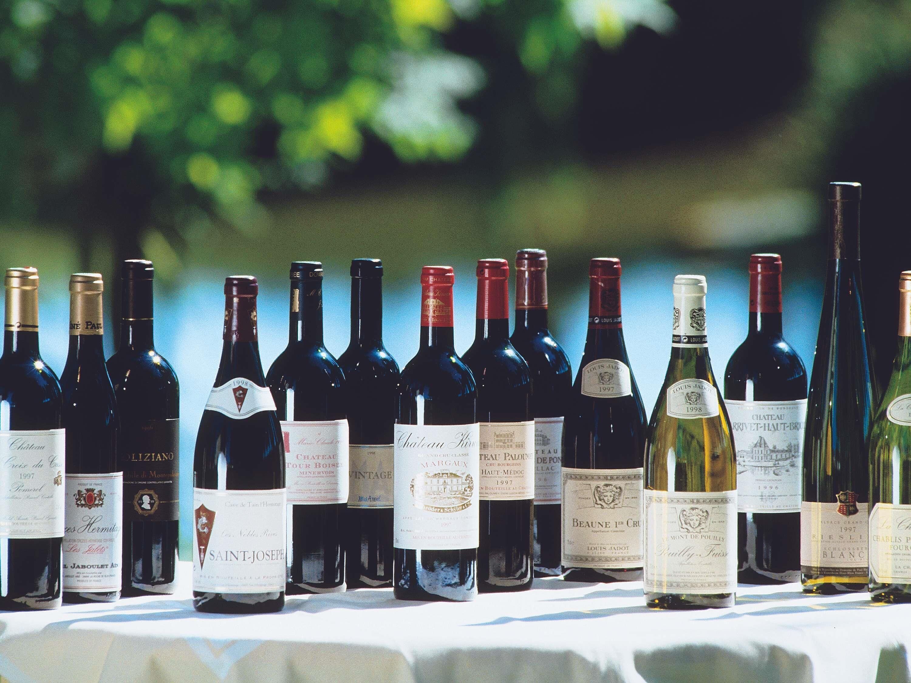 A row of wine bottles on a table with a blurred green background.