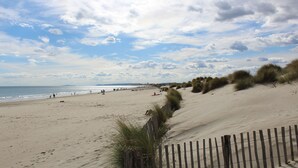 A sandy beach with dunes and a wooden fence. - Mercure Grande Motte Port (La Grande-Motte)