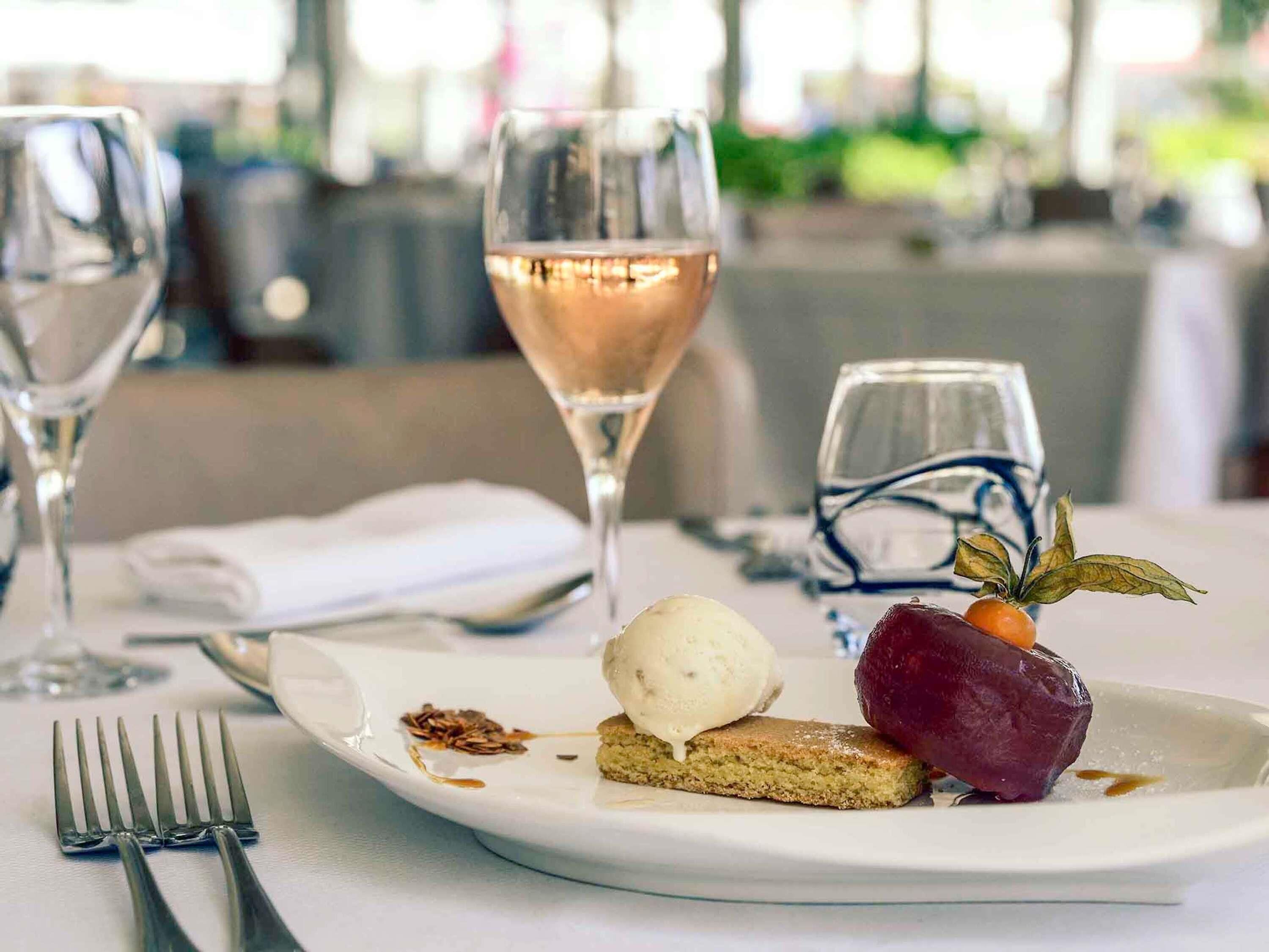 Une assiette à dessert avec une boule de glace, une part de gâteau et une décoration de fruits sur une assiette blanche.