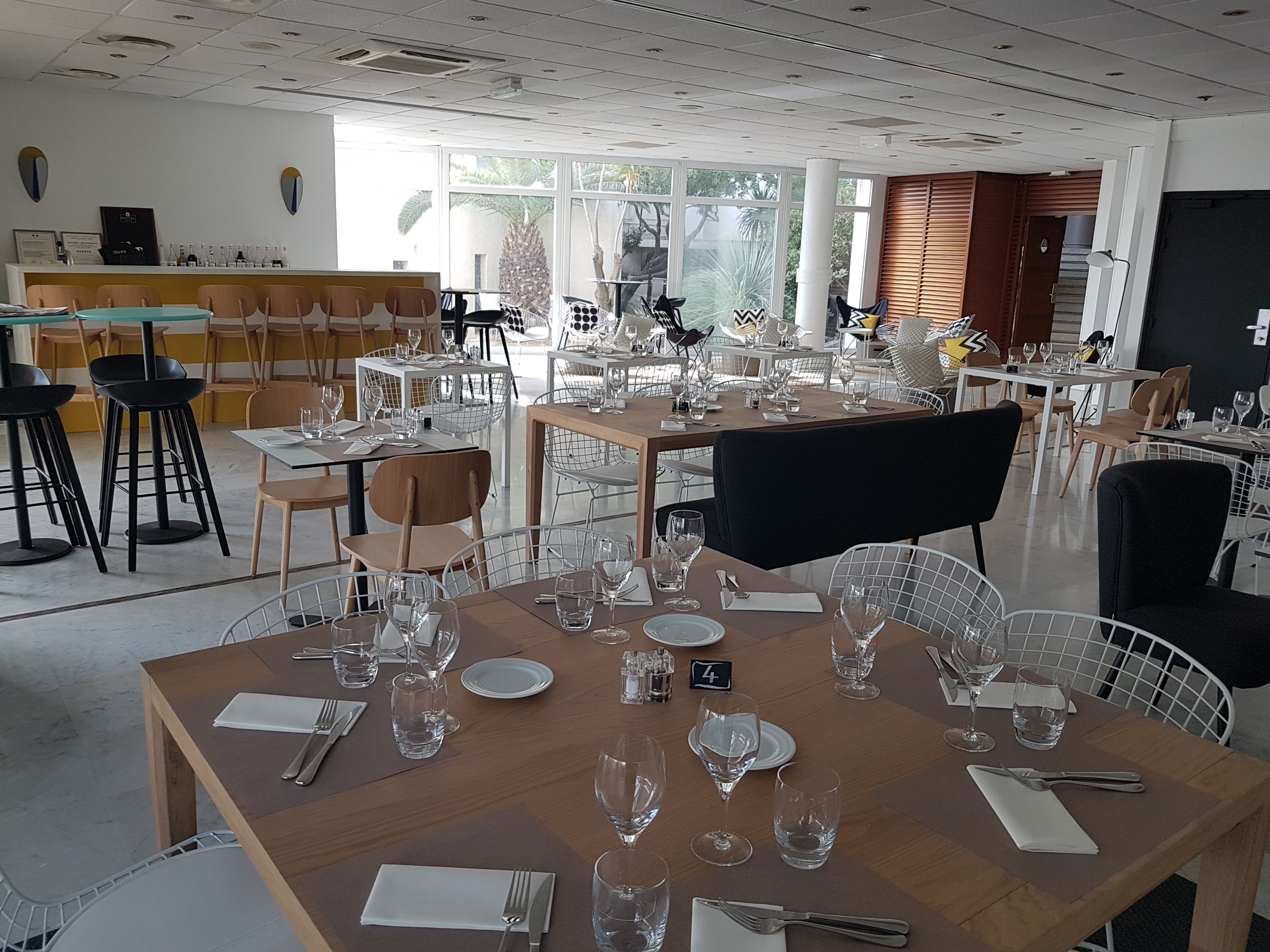 A restaurant with multiple tables set for dining, featuring a mix of metal and wooden chairs.