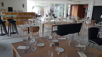 A restaurant with multiple tables set for dining, featuring a mix of metal and wooden chairs.