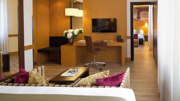 A hotel room with a bed, a desk with a chair, a television, and a view into the hallway.