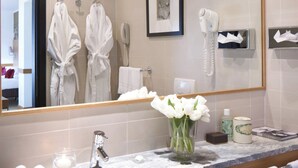 A modern bathroom with a large mirror, two sinks, and a vanity area. There are towels and toiletries on the counter. - Starhotels Tourist (Milan)