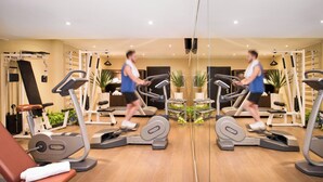 Une salle de sport équipée de tapis de course, d’appareils de musculation et d’un banc.