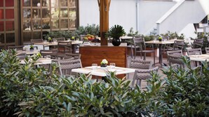 Un espace extérieur aménagé pour les repas, avec des tables et des chaises, entouré de verdure.