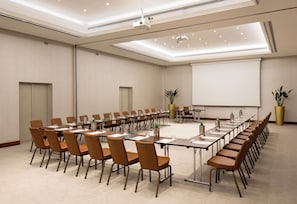 A conference room with a long table, chairs, a projector, and a screen. - Starhotels Tourist (Milan)