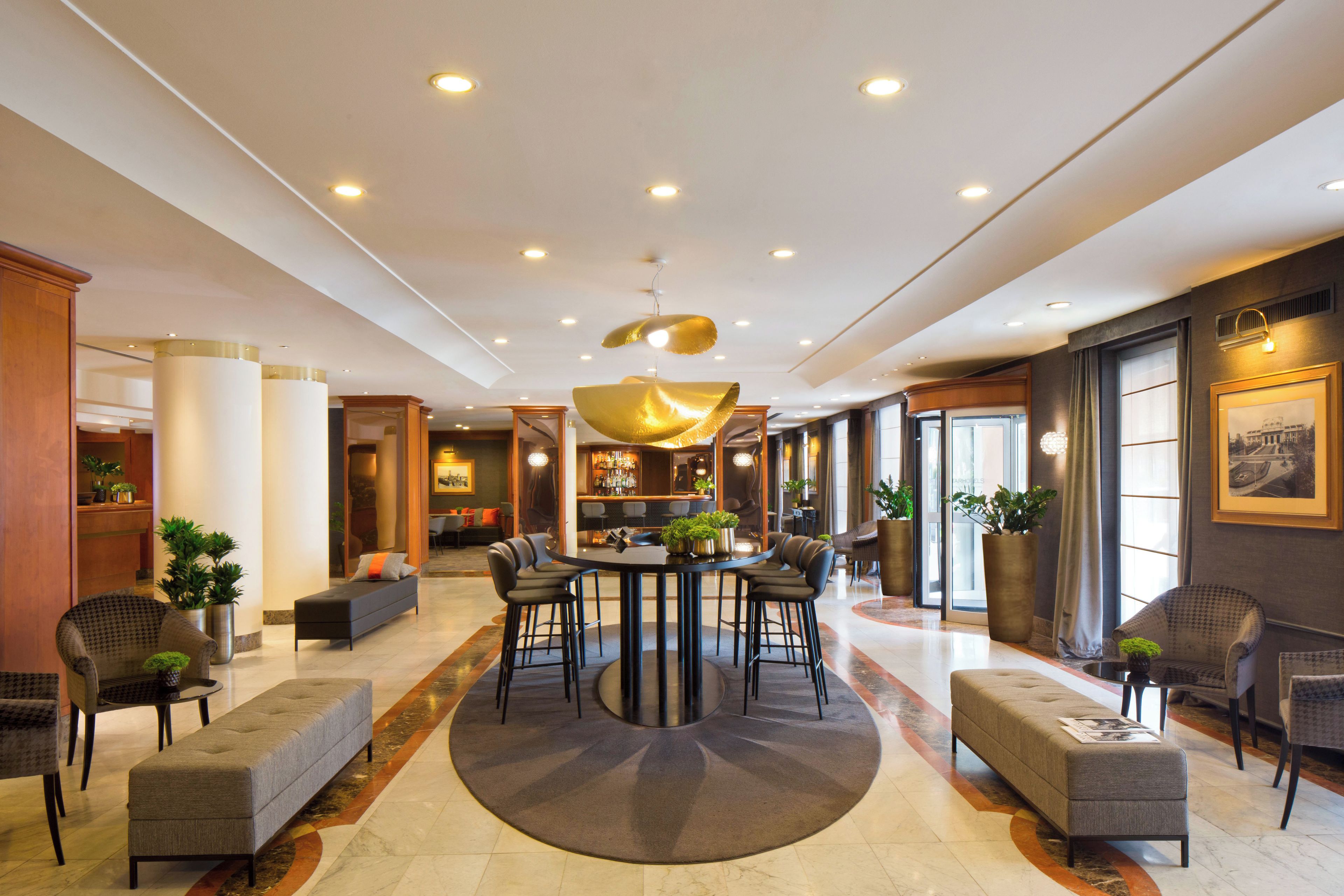 Un hall d’hôtel avec une table ronde, un bar, un coin salon et une grande fenêtre.