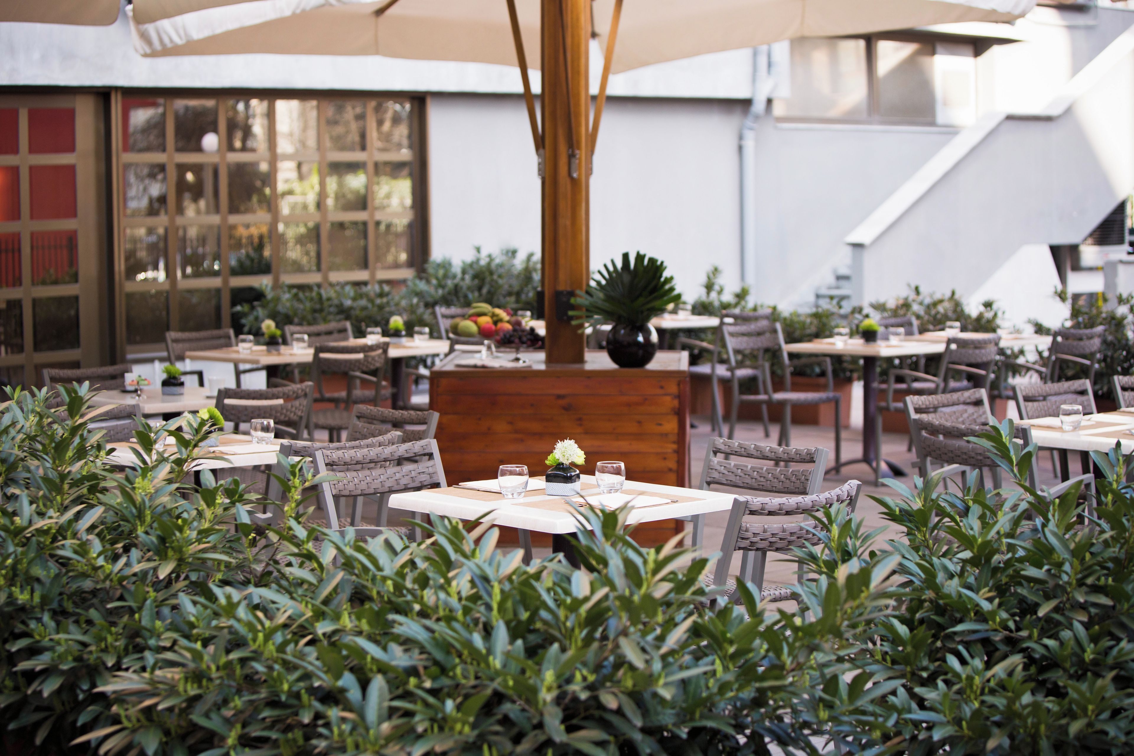 Un'area pranzo all'aperto con diversi tavoli e sedie, immersa nel verde.