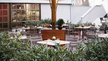 Un'area pranzo all'aperto con diversi tavoli e sedie, immersa nel verde.
