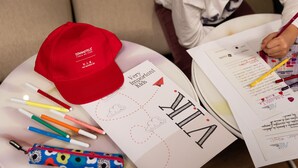 A table with a red cap, various pens, a pencil case, and papers with drawings and writing. - Starhotels Tourist (Milan)
