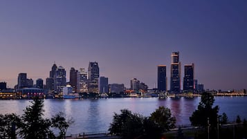 A city skyline at dusk with illuminated buildings along a waterfront.