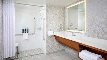 A modern bathroom with a walk-in shower, a vanity with a large mirror, and a towel rack.
