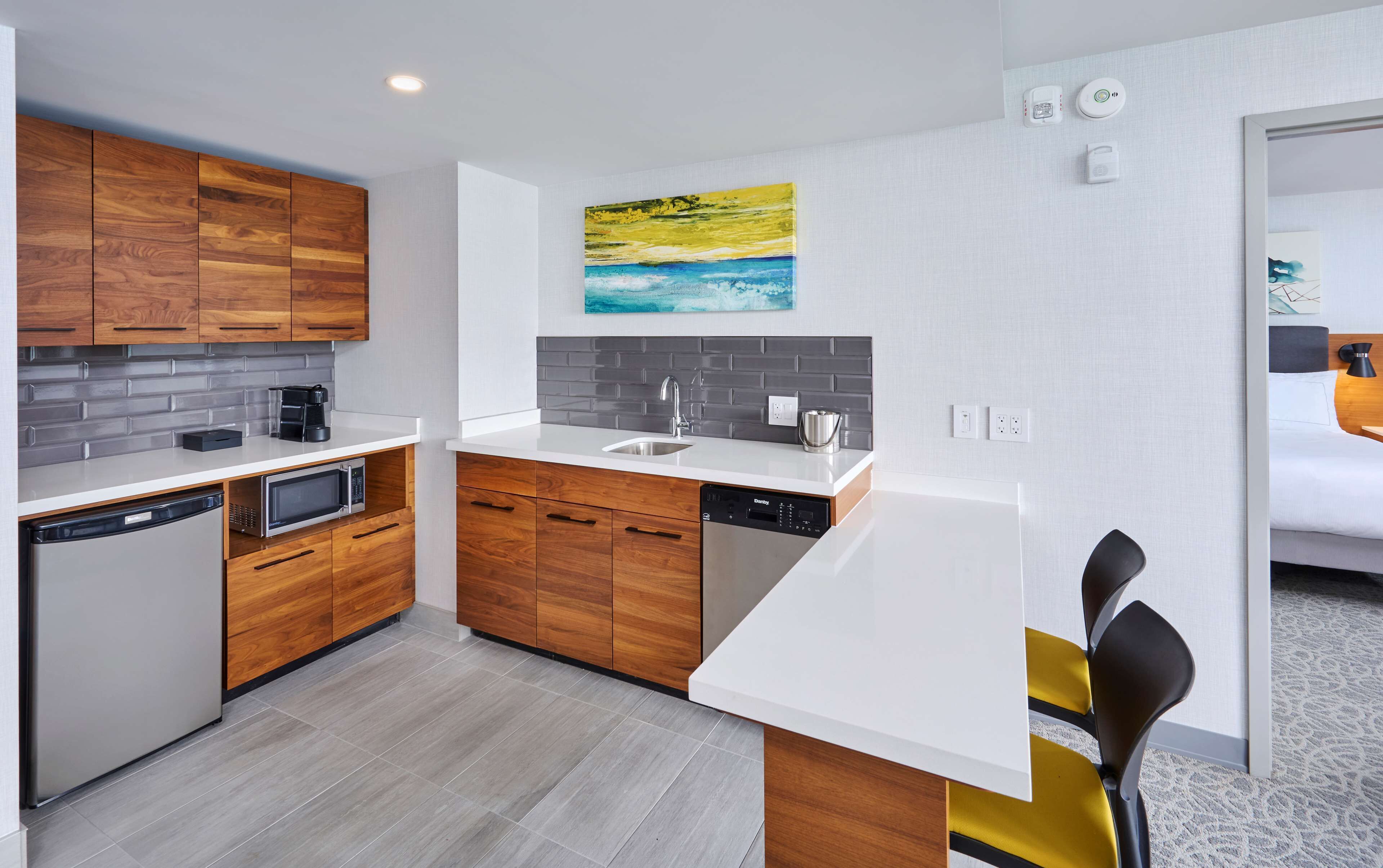 Una cocina moderna con armarios de madera, encimera blanca y salpicadero gris.