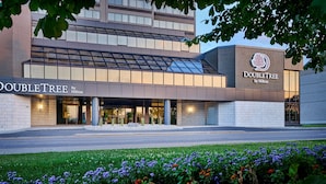 A DoubleTree by Hilton hotel with a modern facade, large glass windows, and a landscaped entrance area.