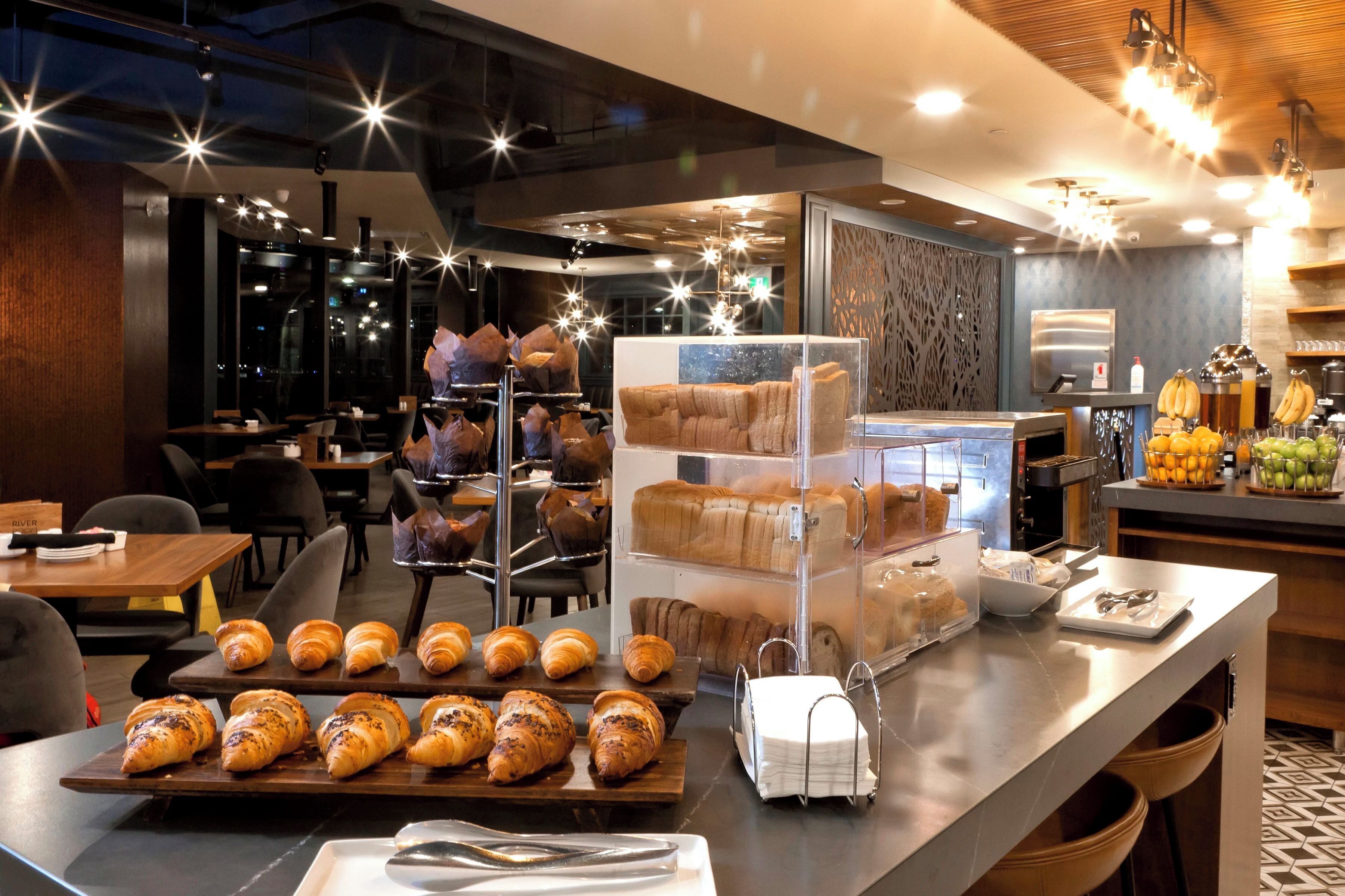 Mostrador de pastelería con bollería y una máquina de café.