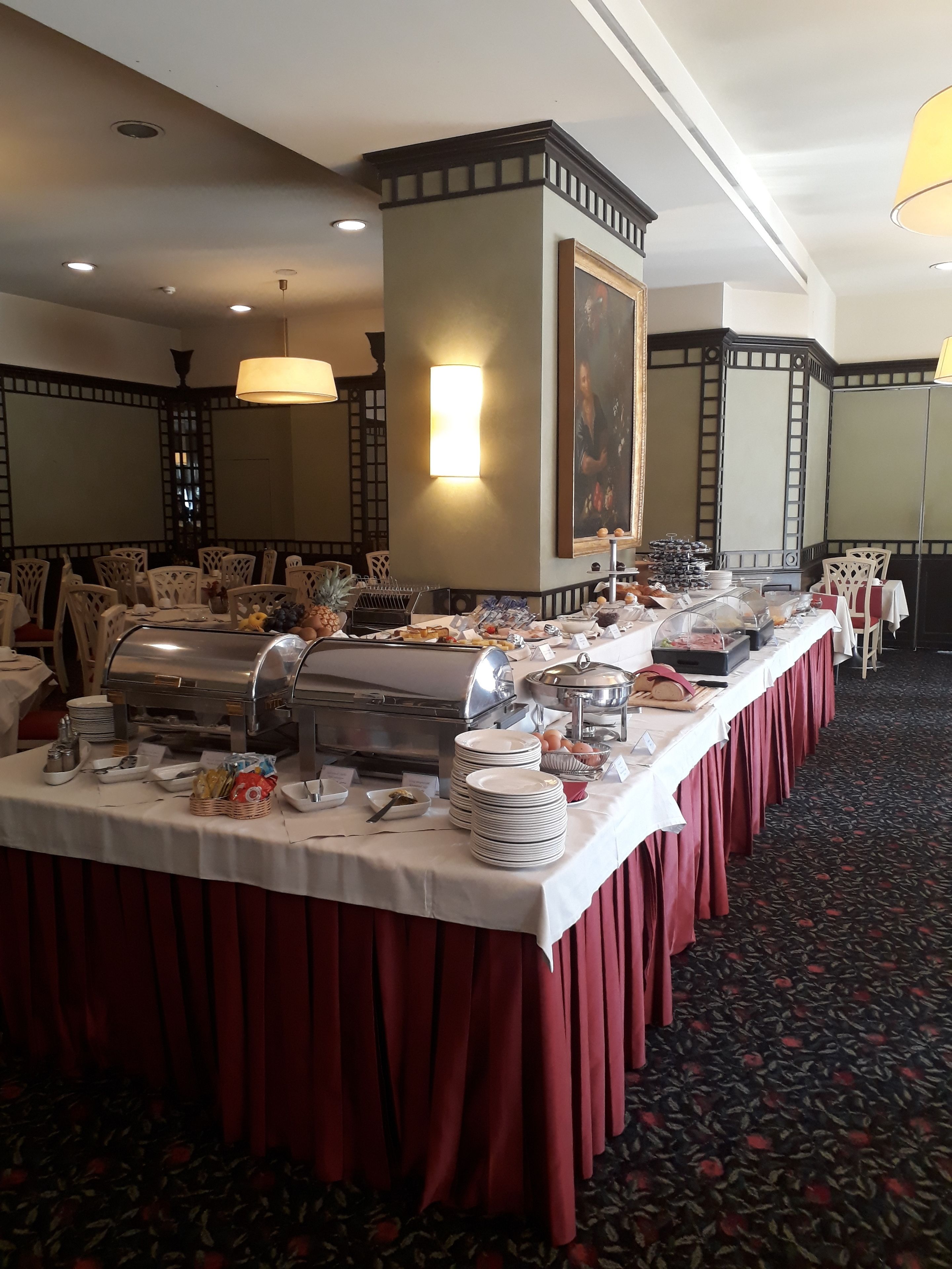 A buffet setup with a variety of food items and a long table covered with a white tablecloth and red table runner.