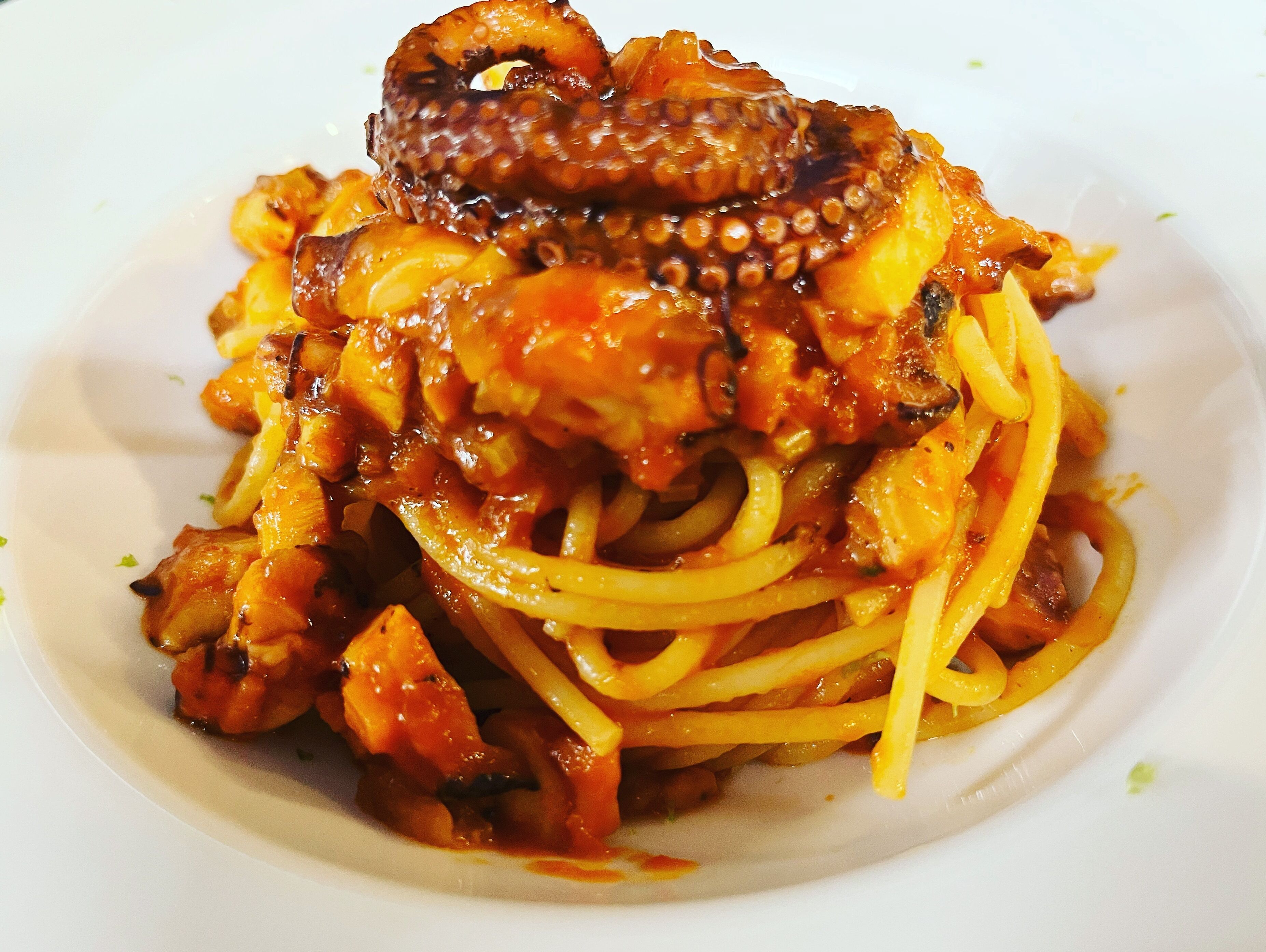 Un plato de espagueti con pulpo y champiñones.