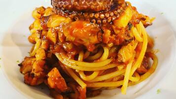 Un plato de espagueti con pulpo y champiñones.