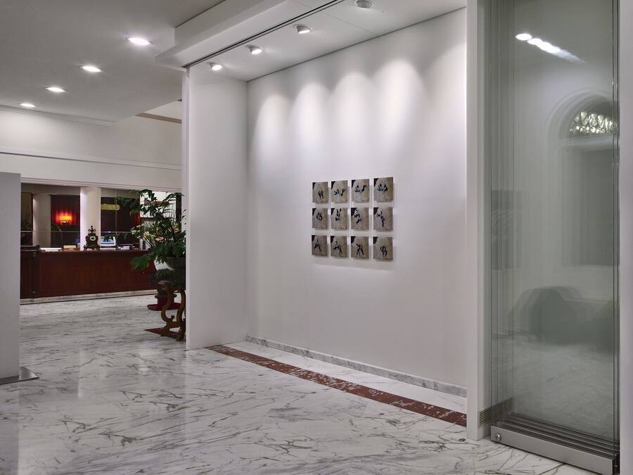 Un hall d’entrée moderne avec un sol en marbre, un comptoir de réception, une porte en verre et un téléviseur fixé au mur.