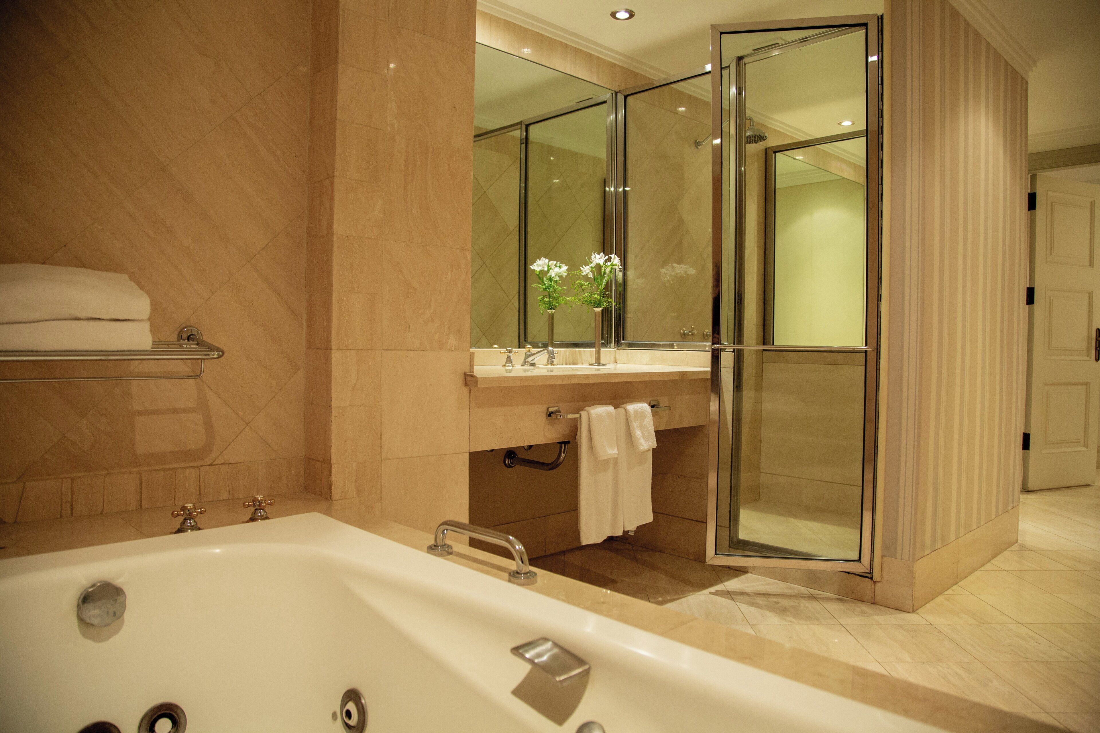 Ein modernes Badezimmer mit einer großen Badewanne, einer Duschkabine und einem Waschtisch mit Spiegel.