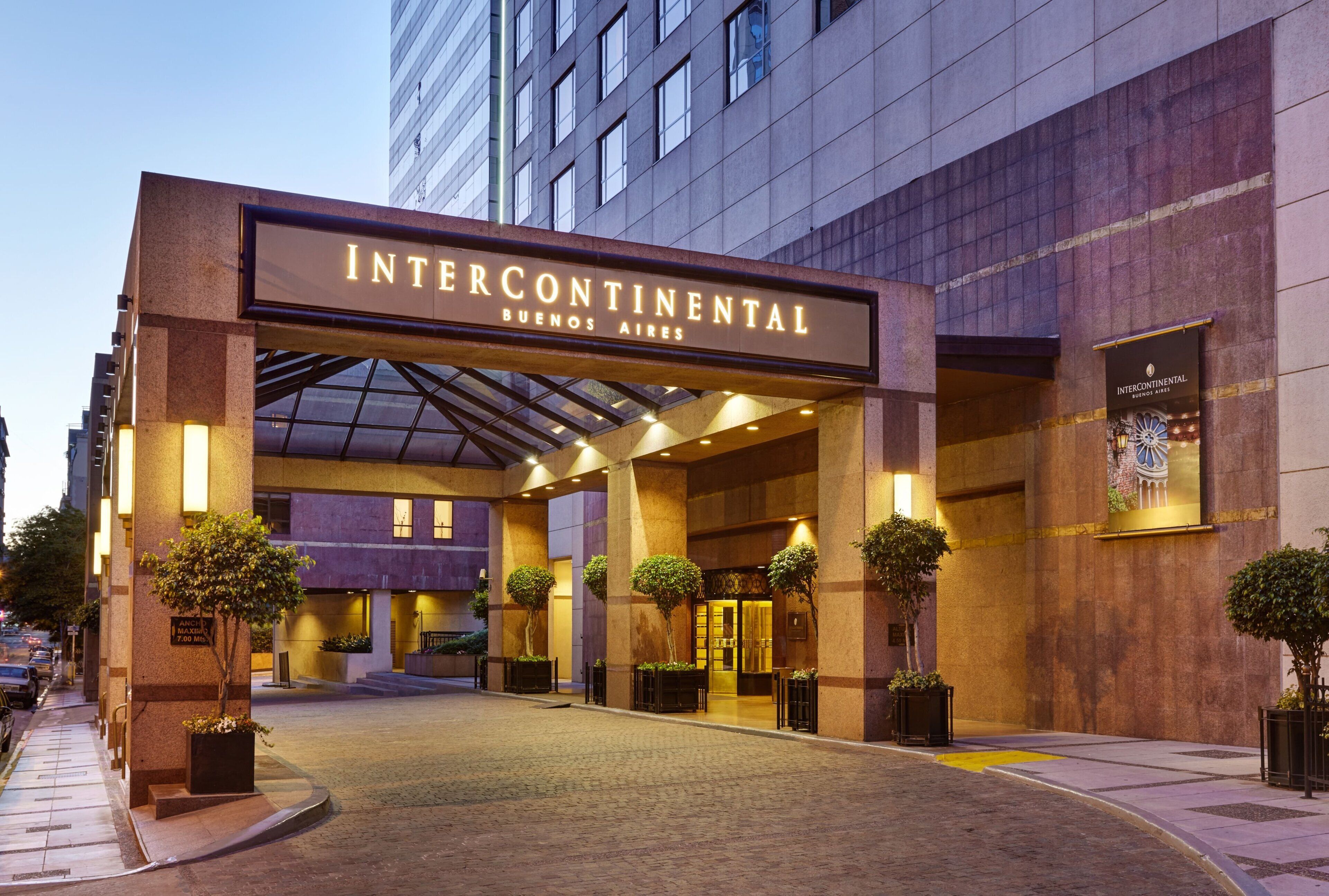 The Intercontinental Buenos Aires hotel entrance with a covered walkway, potted plants, and a clear sky.