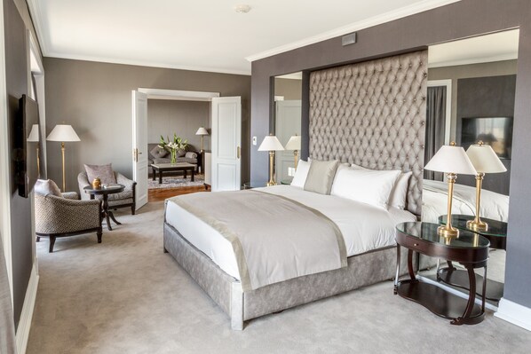A bedroom with a large bed, two bedside tables, a chair, and a mirror.