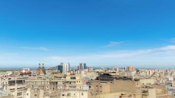 Un paisaje urbano con una combinación de edificios altos y construcciones más antiguas, cielo despejado y una vista distante del mar.