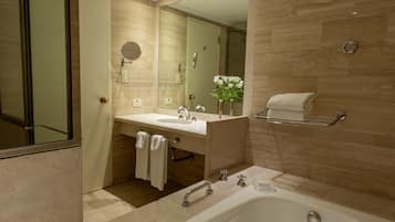 Un baño moderno con un espejo grande, un lavamanos, una bañera y un perchero para toallas.