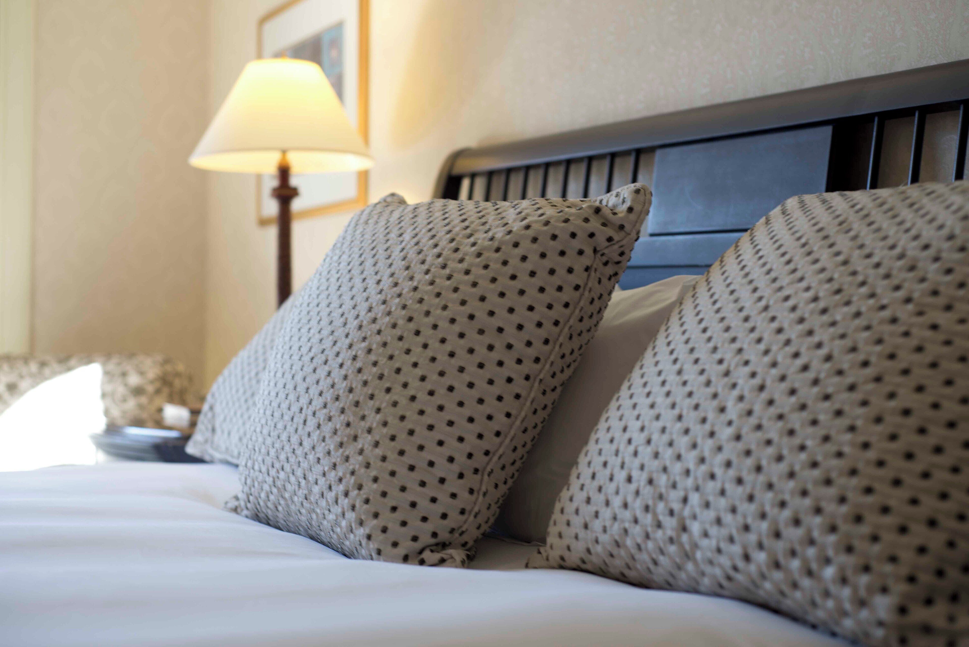 A neatly made bed with patterned pillows and a headboard.