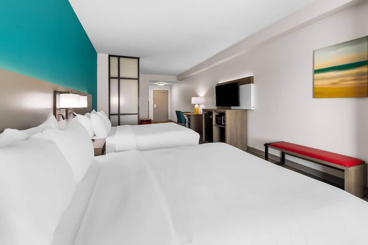 Une chambre d’hôtel avec un grand lit, un bureau, une télévision et un tableau au mur.
