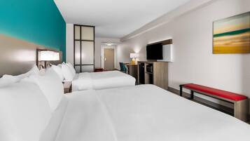 A hotel room with a large bed, a desk, a TV, and a painting on the wall.