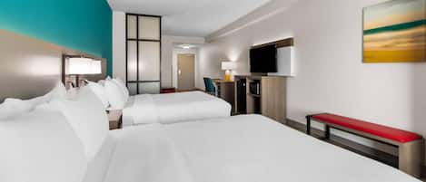 A hotel room with a large bed, a desk, a TV, and a painting on the wall.