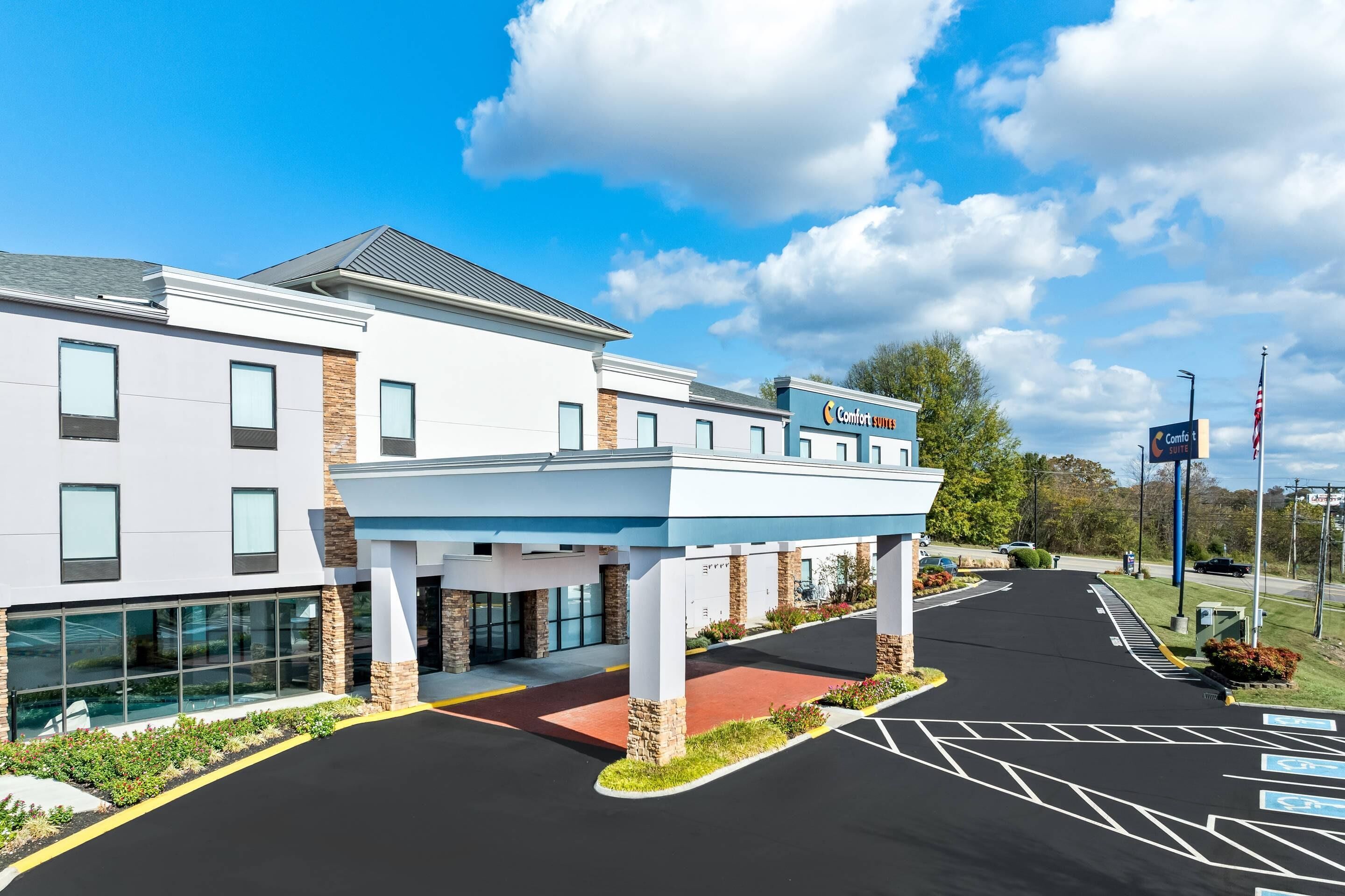 A modern hotel with a covered entrance, a parking lot with handicapped accessibility, and a sign indicating 'Comfort Suites'.