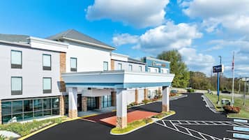 A modern hotel with a covered entrance, a parking lot with handicapped accessibility, and a sign indicating 'Comfort Suites'.