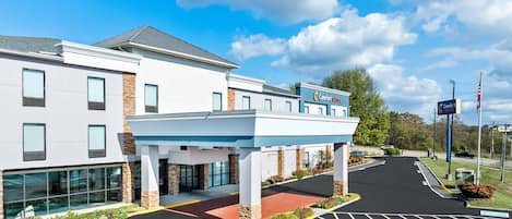 A modern hotel with a covered entrance, a parking lot with handicapped accessibility, and a sign indicating 'Comfort Suites'.