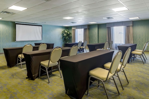 Conference room with a large table, projector screen, and comfortable seating for presentations and meetings.