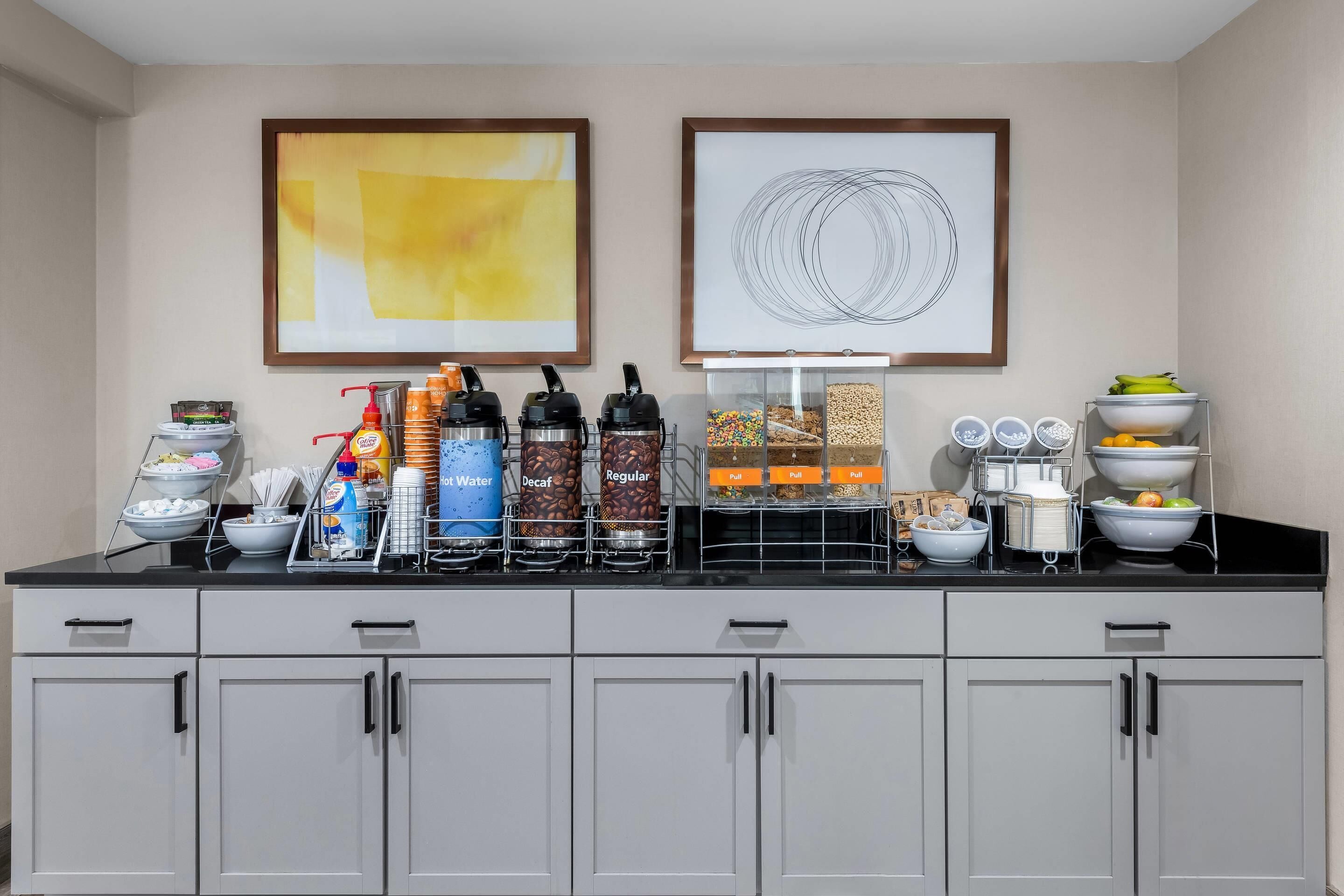 A breakfast bar with various food and drink dispensers, including water, decaf, and regular coffee options.