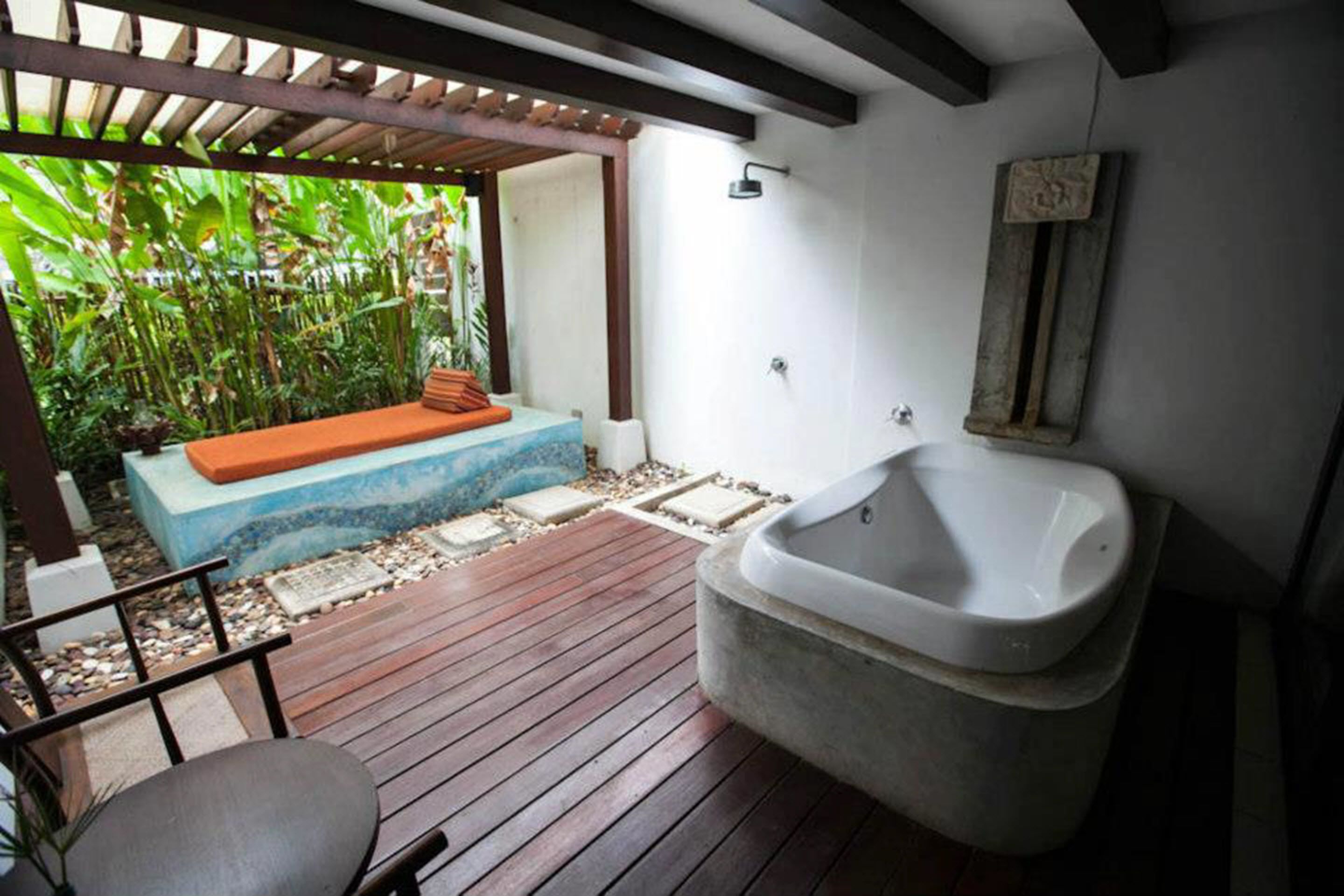 Una terraza de madera con un jacuzzi, un banco y una pequeña mesa.